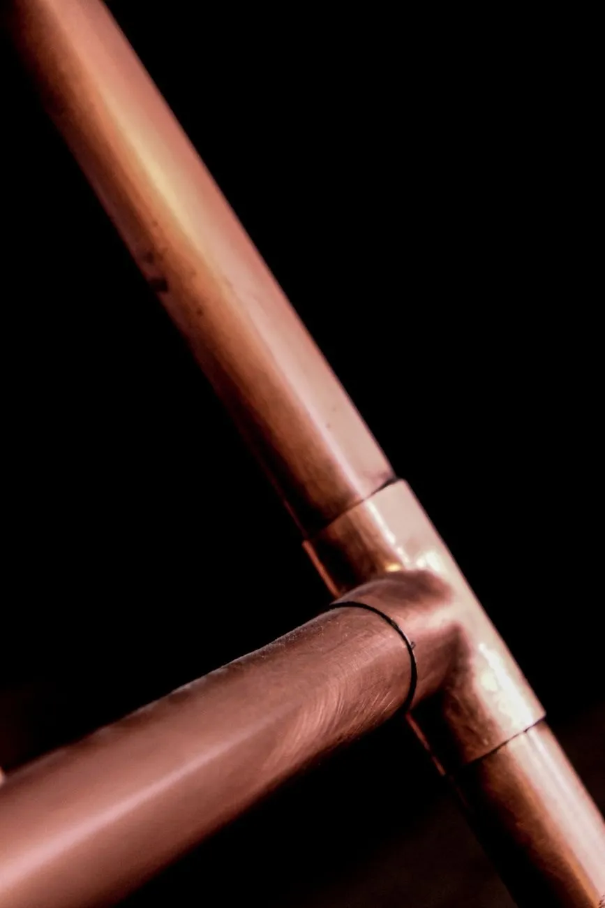 A soldered copper tee joint on dark background