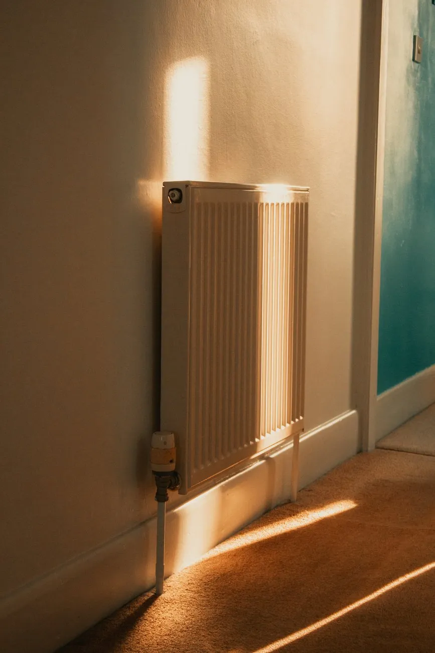 A white panel radiator lit by late afternoon sun in a hallway